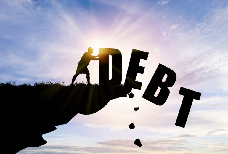Eliminate or get rid of debt concept , Silhouette man pushed off debt wording a cliff with blue cloud sky and sunlight.